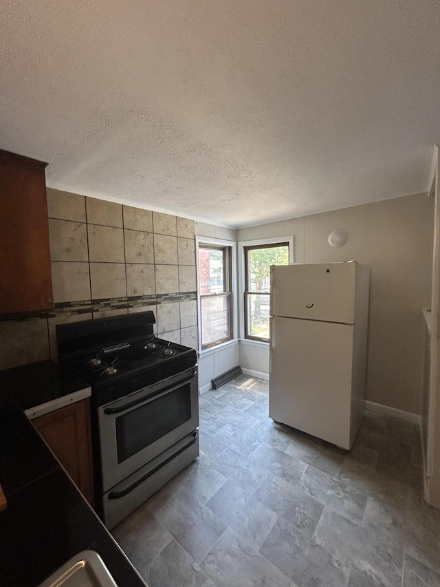 kitchen featuring stainless steel range with gas stovetop, a textured ceiling, and white refrigerator