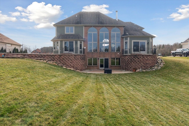 rear view of house featuring a patio, a yard, and brick siding