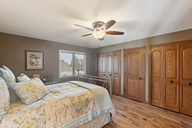 bedroom with a ceiling fan, light wood-type flooring, and two closets