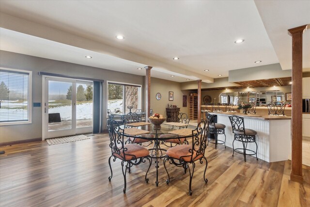 dining space featuring recessed lighting, baseboards, wood finished floors, and ornate columns