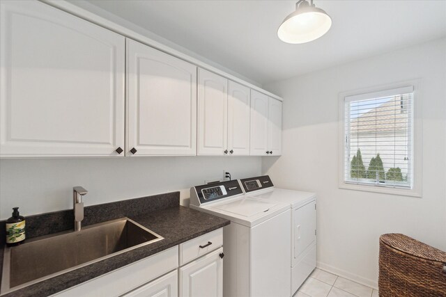 washroom with baseboards, light tile patterned floors, washer and dryer, cabinet space, and a sink