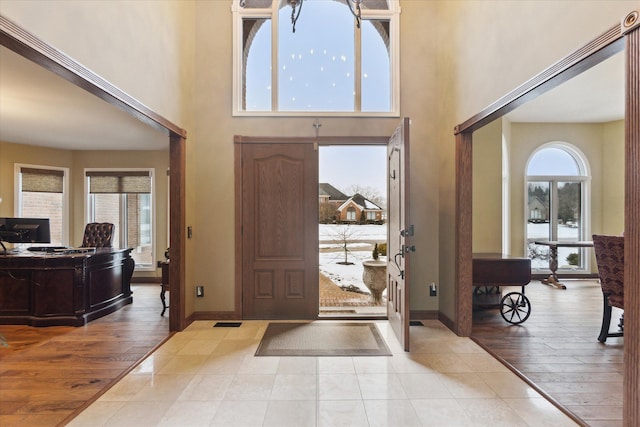 entryway featuring a high ceiling, light wood-type flooring, and baseboards