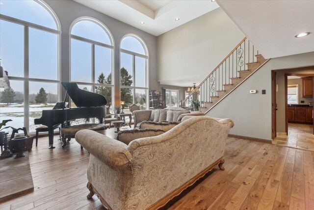 living room with stairs, a wealth of natural light, and light wood finished floors