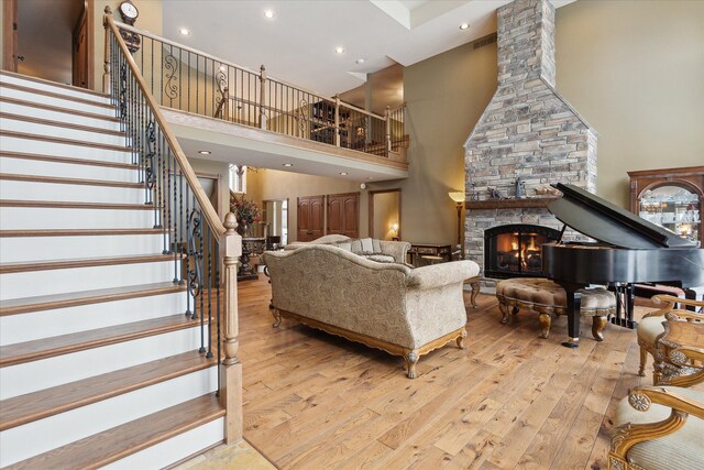 living room featuring hardwood / wood-style floors, stairway, a high ceiling, recessed lighting, and a fireplace