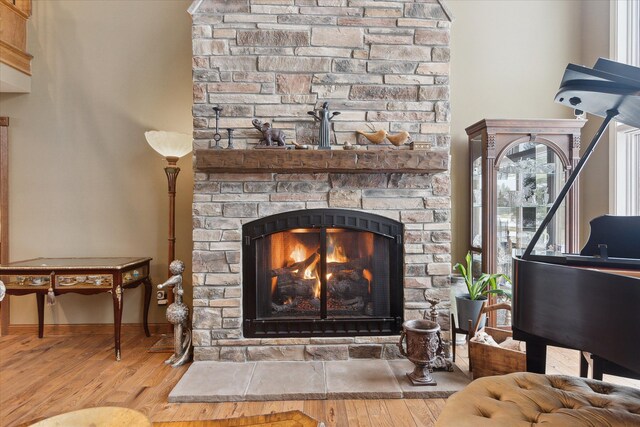 interior details featuring a stone fireplace, baseboards, and wood finished floors