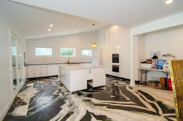 kitchen featuring white cabinetry, lofted ceiling, a center island, and pendant lighting