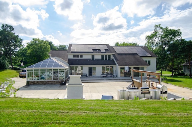 rear view of house with a lawn, glass enclosure, a patio, and solar panels