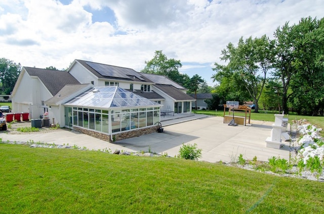 back of house with a lawn, a patio, and solar panels