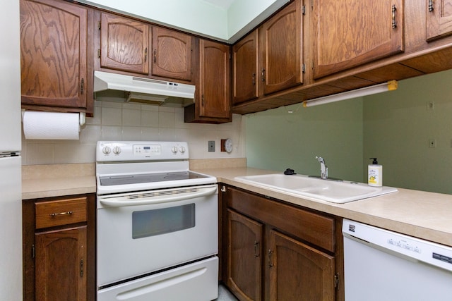 kitchen featuring tasteful backsplash, white appliances, and sink