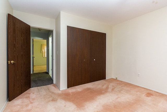 unfurnished bedroom with light carpet and a closet