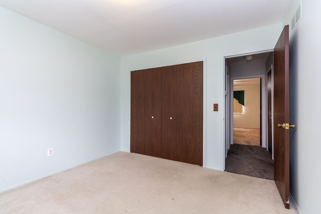 unfurnished bedroom featuring light carpet and a closet