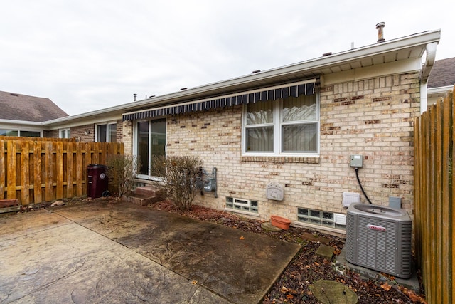 back of property with central AC unit and a patio