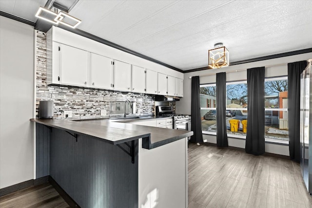 kitchen with tasteful backsplash, white cabinets, dark hardwood / wood-style flooring, and kitchen peninsula