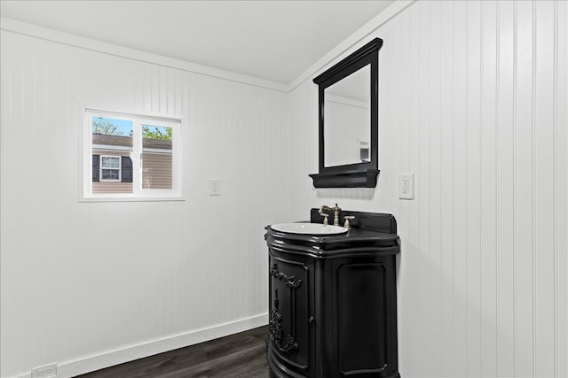 bathroom featuring baseboards, wood finished floors, vanity, and ornamental molding
