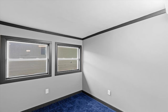 spare room with dark colored carpet, ornamental molding, and baseboards