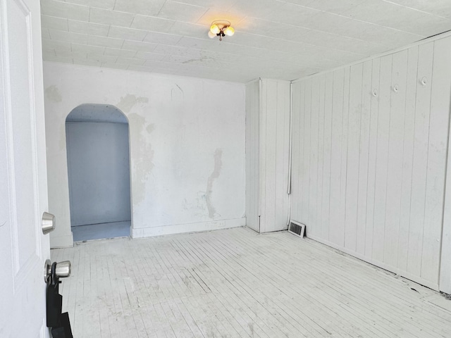 unfurnished room featuring wooden walls