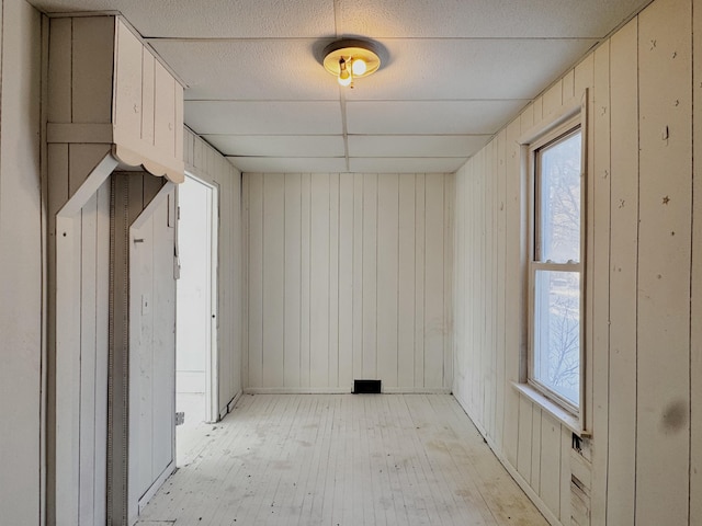 unfurnished room with wooden walls and light wood-type flooring