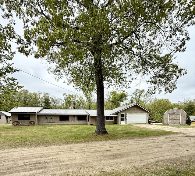 8298 W Hollyhock Ave, Baldwin, MI 49304 - view of front of property with dirt driveway, metal roof, a front lawn, and a garage