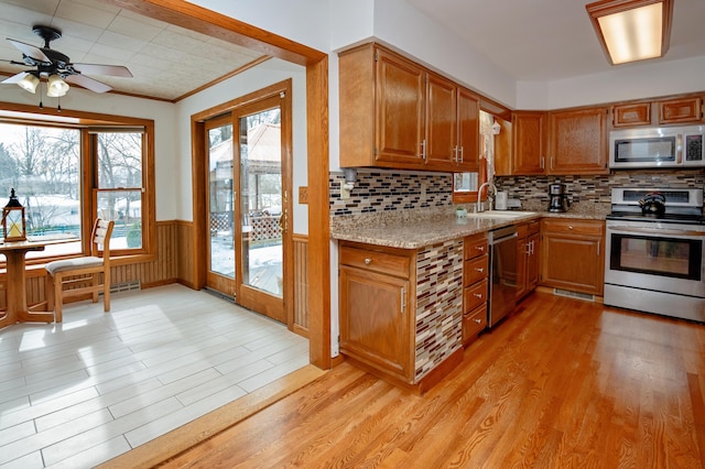 kitchen with light stone counters, appliances with stainless steel finishes, sink, and light hardwood / wood-style floors