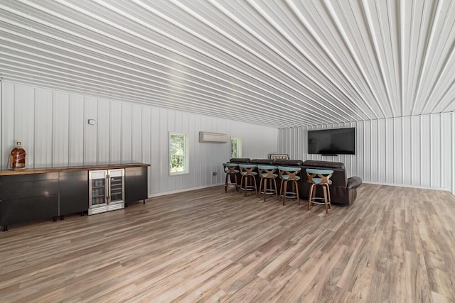 living room with light hardwood / wood-style flooring, a wall mounted AC, and bar area