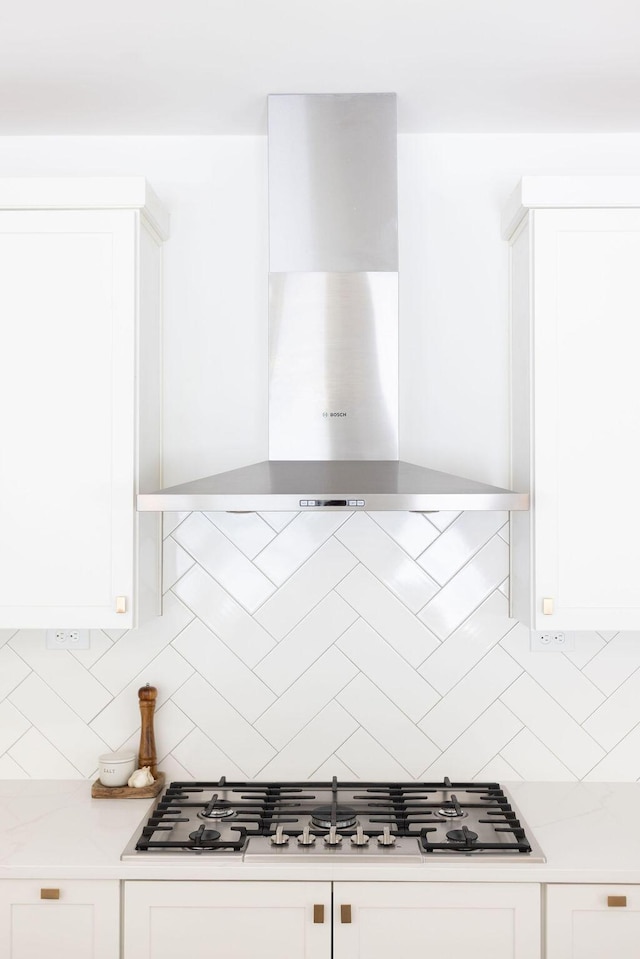 kitchen featuring white cabinetry, wall chimney range hood, and tasteful backsplash