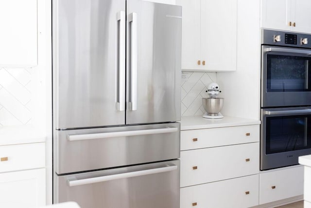 kitchen featuring white cabinetry, stainless steel appliances, and decorative backsplash