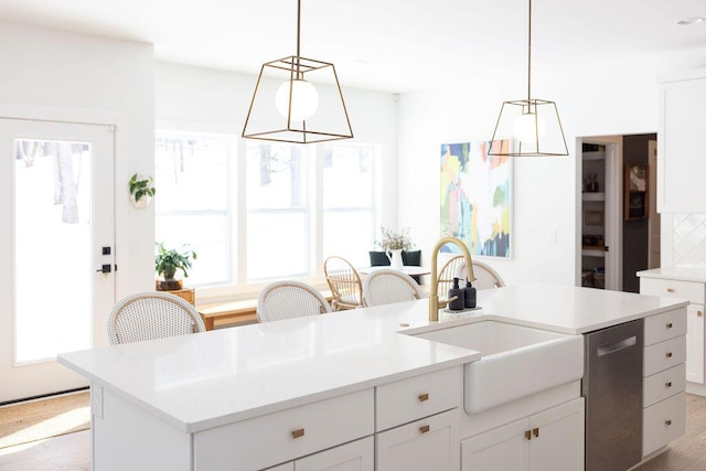 kitchen with sink, decorative light fixtures, stainless steel dishwasher, an island with sink, and white cabinets