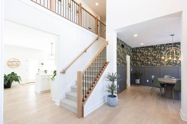 stairway featuring a notable chandelier, a towering ceiling, and wood-type flooring