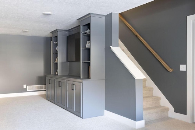 stairway featuring carpet and a textured ceiling