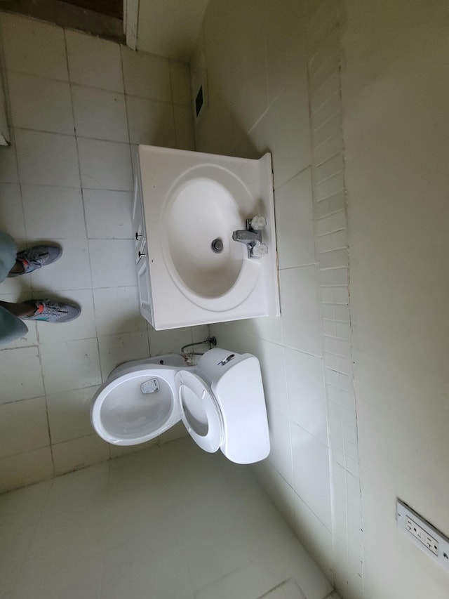 bathroom with tile walls, sink, and toilet