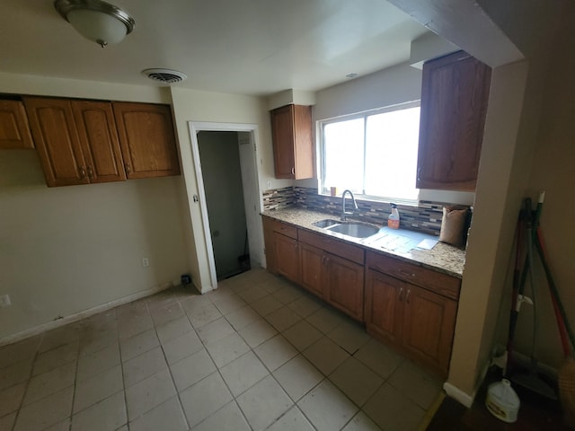 kitchen featuring light stone counters, sink, decorative backsplash, and light tile patterned floors