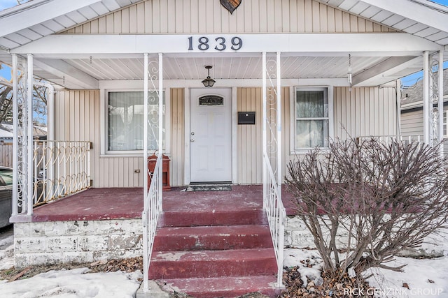 snow covered property entrance with covered porch