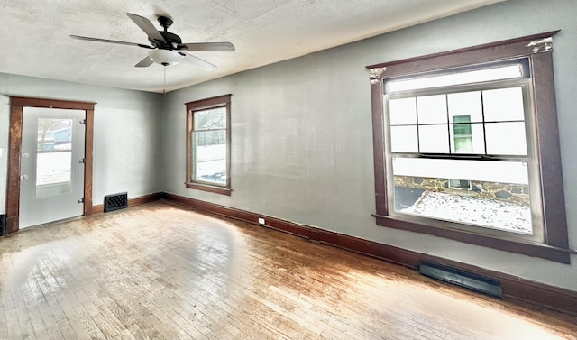 unfurnished room with a textured ceiling, ceiling fan, and light hardwood / wood-style flooring