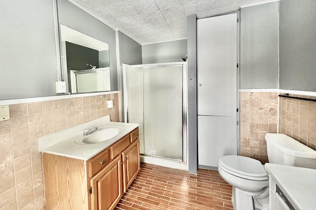 bathroom with vanity, tile walls, an enclosed shower, and toilet