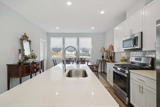 kitchen with backsplash, stainless steel appliances, light stone countertops, and white cabinets