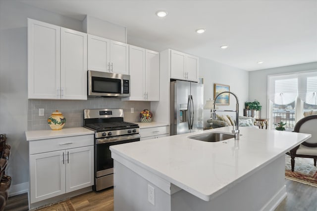 kitchen featuring sink, appliances with stainless steel finishes, tasteful backsplash, an island with sink, and white cabinets