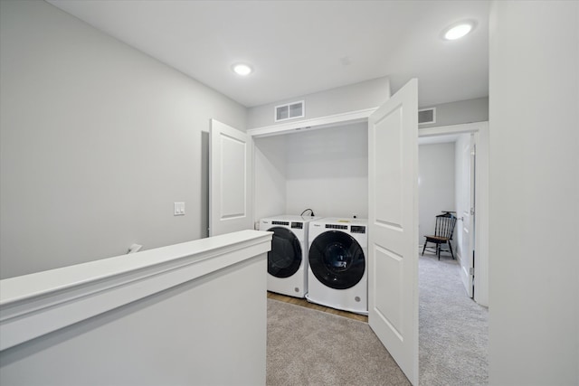 laundry area featuring light colored carpet and washer and clothes dryer