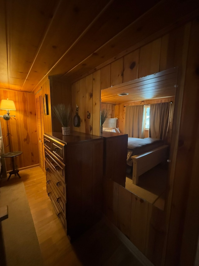 bedroom with wooden walls and light hardwood / wood-style floors