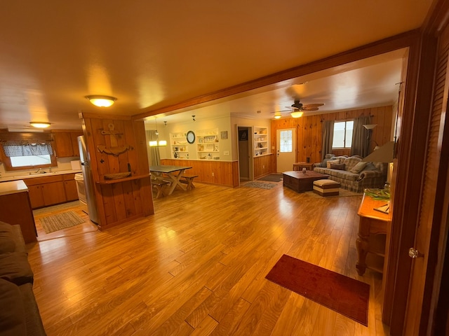 living room with sink, wood walls, ceiling fan, and light hardwood / wood-style flooring