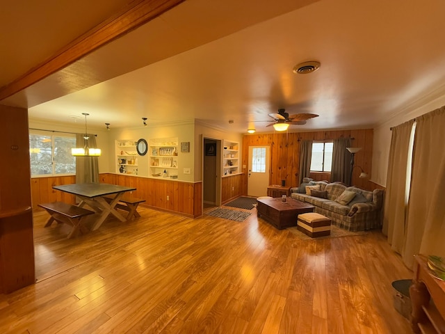 living room with a wealth of natural light, wooden walls, and light wood-type flooring