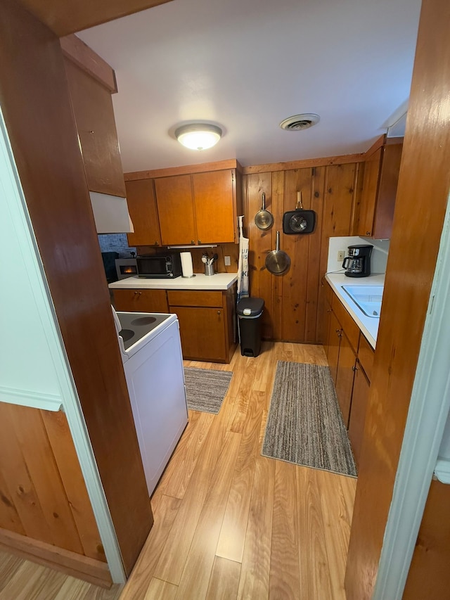 kitchen featuring wood walls, light wood-type flooring, and electric range