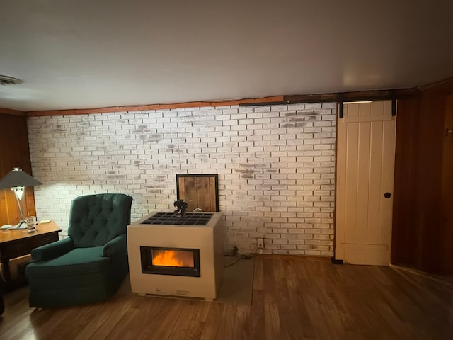 unfurnished room featuring wood-type flooring and brick wall