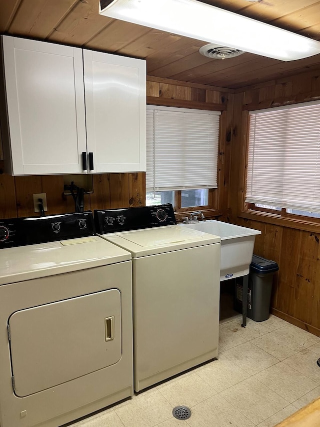 laundry area featuring cabinets, wooden ceiling, washing machine and dryer, and wood walls