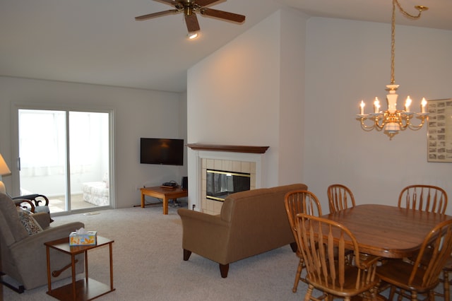 carpeted dining room with a tiled fireplace, ceiling fan with notable chandelier, and high vaulted ceiling