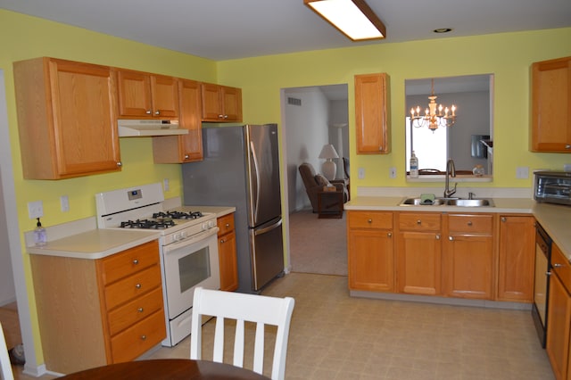 kitchen featuring sink, white gas stove, decorative light fixtures, a chandelier, and stainless steel refrigerator