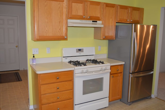 kitchen with white range with gas cooktop and stainless steel fridge