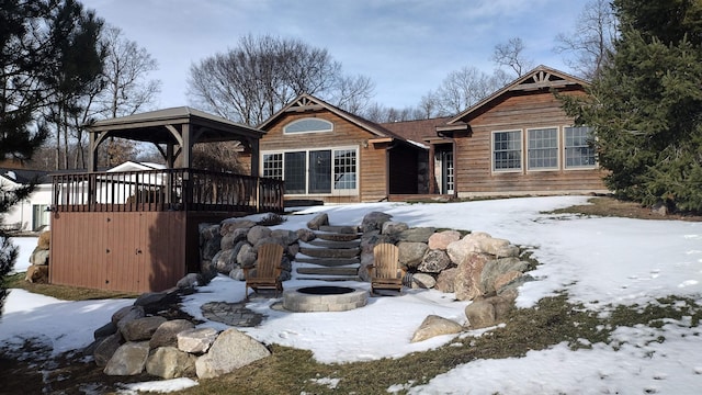 snow covered back of property featuring a gazebo, an outdoor fire pit, and a deck