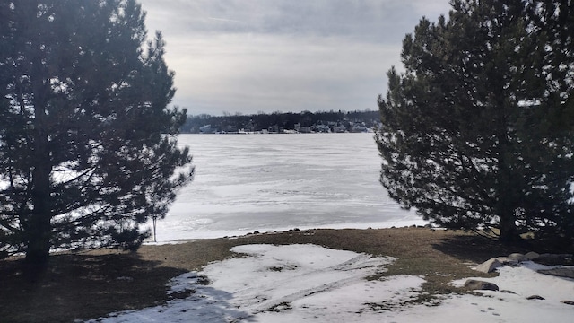 yard covered in snow featuring a water view