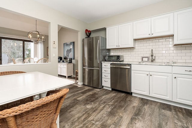 kitchen with sink, white cabinets, hanging light fixtures, stainless steel appliances, and dark wood-type flooring