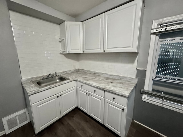 kitchen with dark hardwood / wood-style flooring, sink, decorative backsplash, and white cabinets